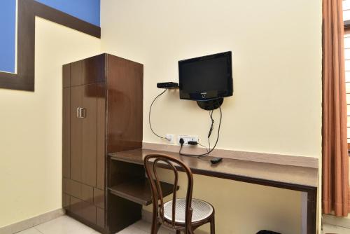 a room with a desk with a tv and a chair at Hotel Galaxy in Dehradun