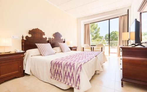 a bedroom with a large bed and a television at Hotel Gaya in Paguera