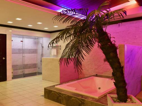 uma palmeira numa casa de banho com uma parede rosa em Xin Yuan Motel em Taichung