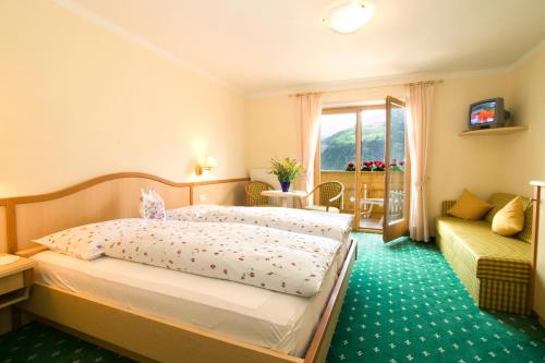 シェーナにあるHotel Garni Alpenhofのベッドとソファ付きのホテルルーム