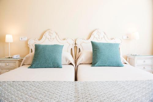 a bedroom with two beds with blue pillows at Hotel Gaya in Paguera