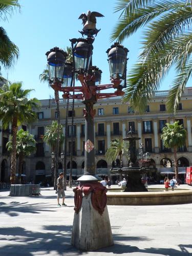 a street light with birds on it in front of a building at Roma Reial in Barcelona