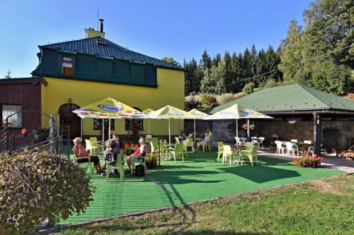 a group of people sitting on a patio with umbrellas at Penzion Vyhlídka Janovičky in Broumov