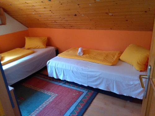 two beds in a room with orange walls at Margó Nyaraló in Balatonederics