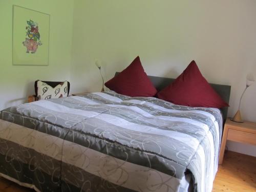 ヴェルト・アン・デア・ドナウにあるWaldesruh & Waldeslustの赤い枕が付いたベッドが備わる客室です。