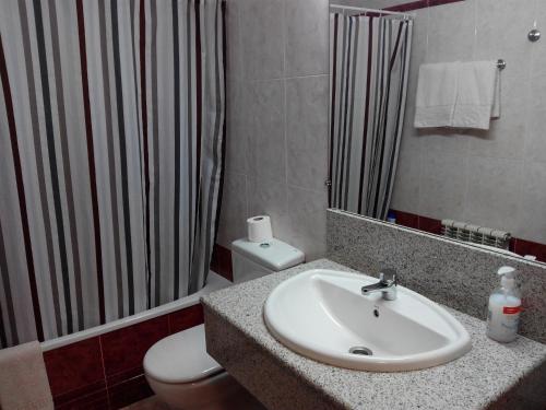 een badkamer met een wastafel, een toilet en een spiegel bij Apartamentos Querol in Valderrobres