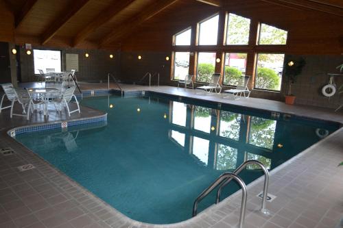 uma grande piscina com cadeiras e uma mesa em Cobblestone Hotel & Suites - Wisconsin Rapids em Wisconsin Rapids