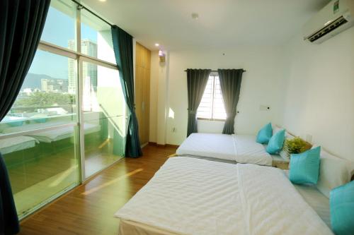two beds in a room with a large window at DaNa Home Hotel - Apartment in Da Nang