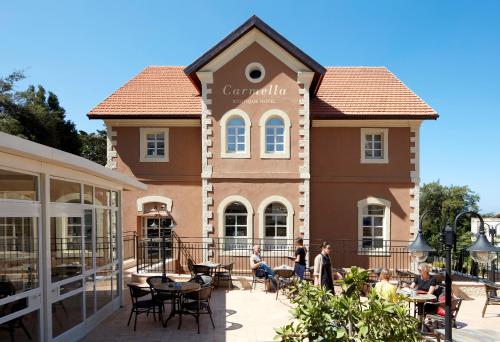a building with people sitting at tables in front of it at Carmella Boutique Hotel in Haifa