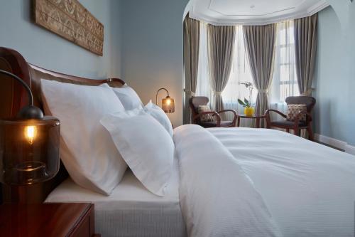 a bedroom with a white bed with white pillows at Carmella Boutique Hotel in Haifa