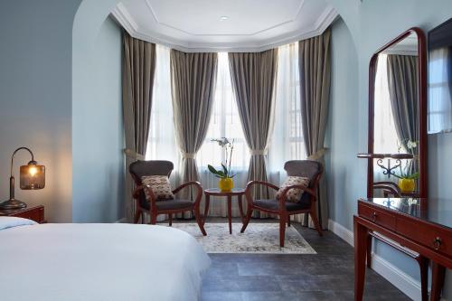 a bedroom with a bed and a table and chairs at Carmella Boutique Hotel in Haifa