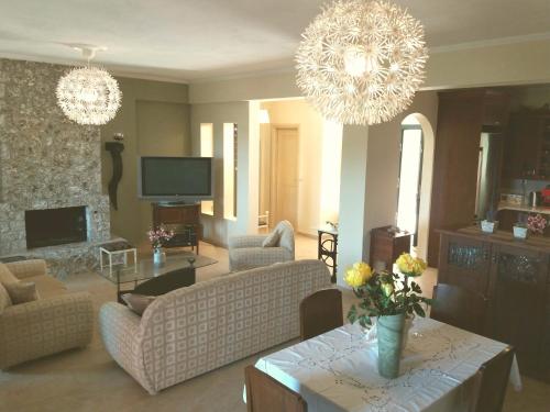 Corfu Villa Galini في Potamós: غرفة معيشة مع أريكة وطاولة مع زهور