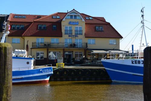 dos barcos atracados en el agua frente a un edificio en Gołąbek Łeba en Łeba