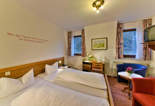 a bedroom with a bed and a desk and a tv at Hotel & Restaurant Krone in Kestert