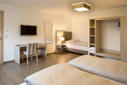 - une chambre avec 2 lits, un bureau et une télévision dans l'établissement Ferienwohnung zur Schönen Aussicht-Rüters Parkhotel, à Willingen