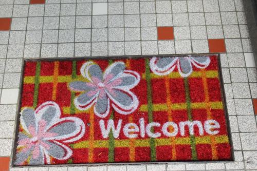 a welcome mat on a tiled floor with flowers at Appartement Val de Saône in Seurre