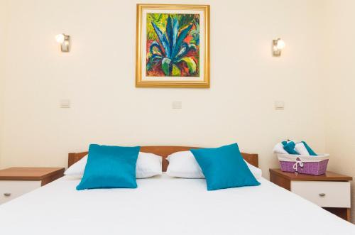 a bedroom with a white bed with blue pillows at Apartments Dora Mljet in Kozarica