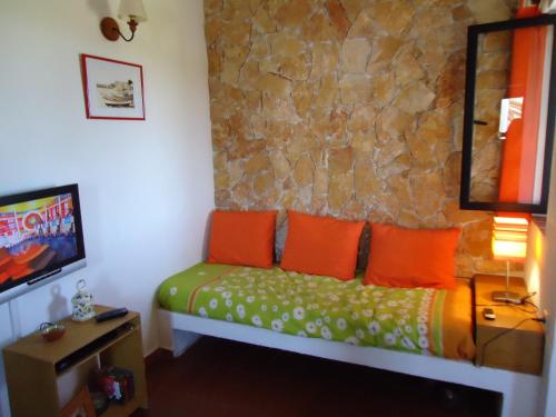 a room with a bed with orange pillows and a stone wall at Apartamento em Pedras del Rei in Moncarapacho