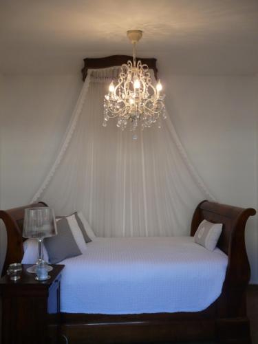 a bedroom with a bed with a chandelier at MAISON Classée 3* in Gujan-Mestras