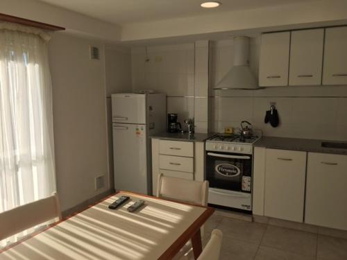 La cuisine est équipée d'une table, d'une cuisinière et d'un réfrigérateur. dans l'établissement Duplex Colina de Peralta Ramos, à Mar del Plata