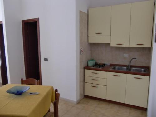ランペドゥーザにあるVittorio Emanuele Apartmentsのキッチン(テーブル、シンク、白いキャビネット付)