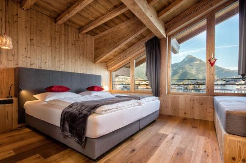 een slaapkamer met een groot bed en een groot raam bij hubertus dolomites in Fiè