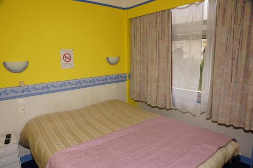 a small bedroom with a bed and a window at Le Richelieu in Le Boulou