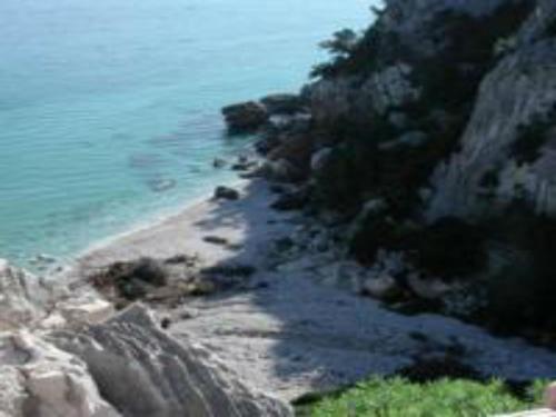 a beach with rocks and the ocean on a mountain at Hotel San Francisco in Cala Gonone