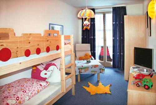 a childs bedroom with a bunk bed and a television at Ferienhotel Barmsee in Krün