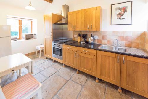 a kitchen with wooden cabinets and a sink at Whitley Coach House in Whitley