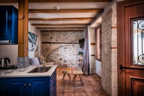 a kitchen with blue cabinets and a stone wall at Veneziano Boutique Hotel in Heraklio