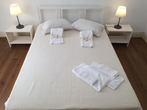 a large white bed with white towels and two lamps at Apartamento Casino Praia II in Figueira da Foz