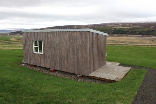 eine kleine Holzhütte auf einem Grasfeld in der Unterkunft Fornhagi 2 in Akureyri