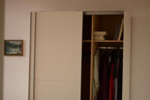 a white refrigerator in a closet next to a shelf at Ferienwohnung in der schönen Rattenfängerstadt in Hameln