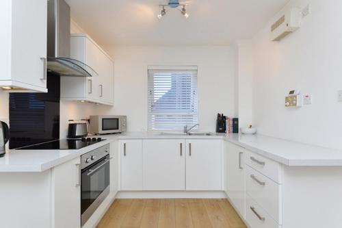 エディンバラにあるEdinburgh Seaside Apartmentの白いキッチン(白いキャビネット、シンク付)