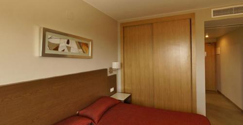 a bedroom with a red bed and a wooden headboard at Hotel Ciutat de Carlet in Carlet