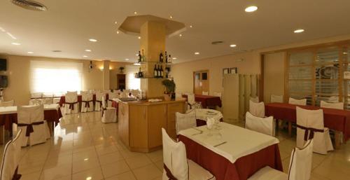 un restaurante con mesas blancas y sillas blancas en Hotel Ciutat de Carlet, en Carlet