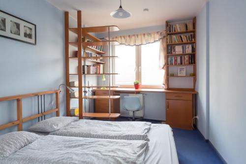 a bedroom with a bed and a desk and book shelves at Apartament Nadmorski in Gdańsk