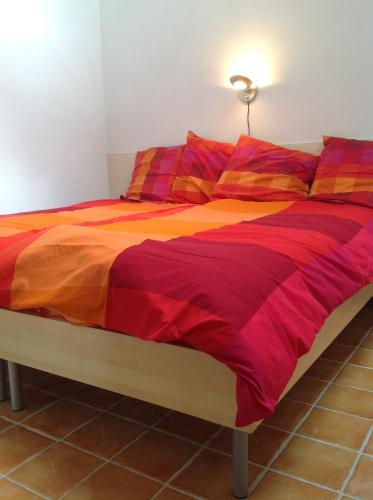 a bed with a colorful comforter on it at Beeldend Buiten in Wichmond