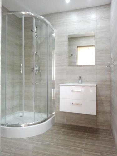 a bathroom with a glass shower and a sink at Lazur Resort in Rogowo