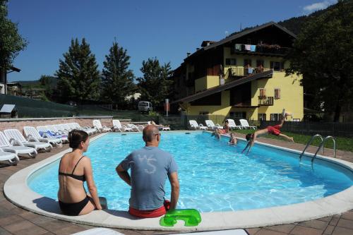 a man and a woman sitting next to a swimming pool at Albergo Casavecchia in Tiarno di Sopra