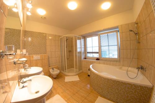 a bathroom with a tub and a sink and a toilet at Wellness Hotel Hukvaldy POLOPENZE A WELLNESS V CENĚ in Příbor