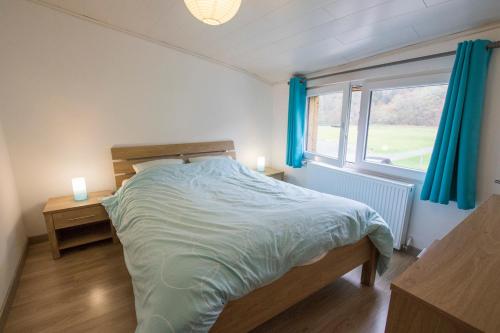 Schlafzimmer mit einem Bett und einem Fenster mit blauen Vorhängen in der Unterkunft l'oiseau d'eau in Bouillon