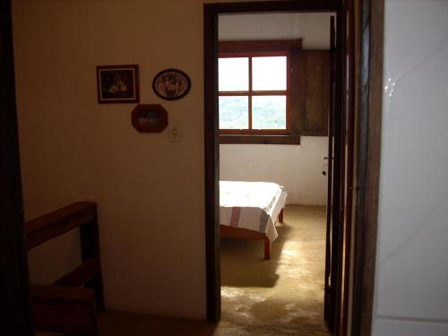 Schlafzimmer mit einem Bett, einem Fenster und einer Tür in der Unterkunft Homestay Tiradentes Alto da Torre in Tiradentes
