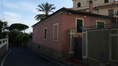 a pink house with a palm tree behind it at Casa vacanze Cristina in Imperia