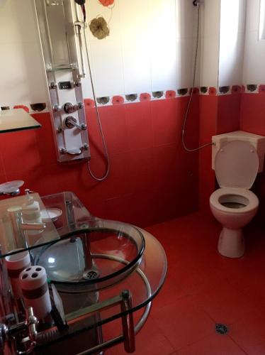a red bathroom with a toilet and a glass sink at Guest House Pautalya in Kyustendil