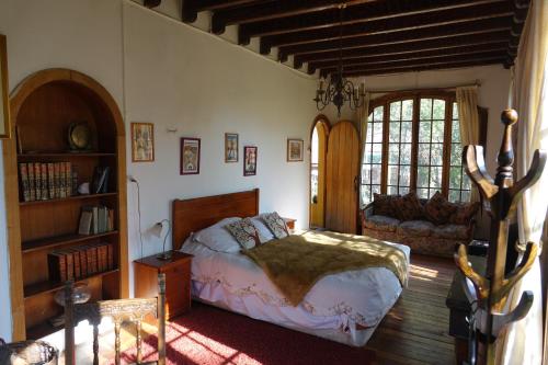 1 dormitorio con cama y sofá en Hostal Los Castaños, en San Alfonso