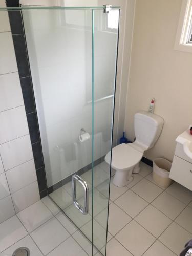 a bathroom with a toilet and a glass shower at Mount View Motel Hawera in Hawera