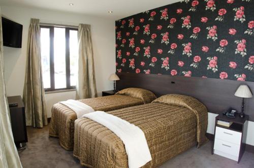Habitación de hotel con 2 camas y pared de flores en The Famous Grouse Hotel en Lincoln
