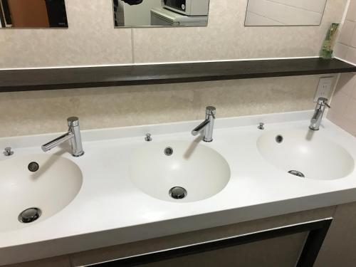 two sinks in a bathroom with two faucets at Guest House Kuranomachi ゲストハウス蔵の街 in Tochigi